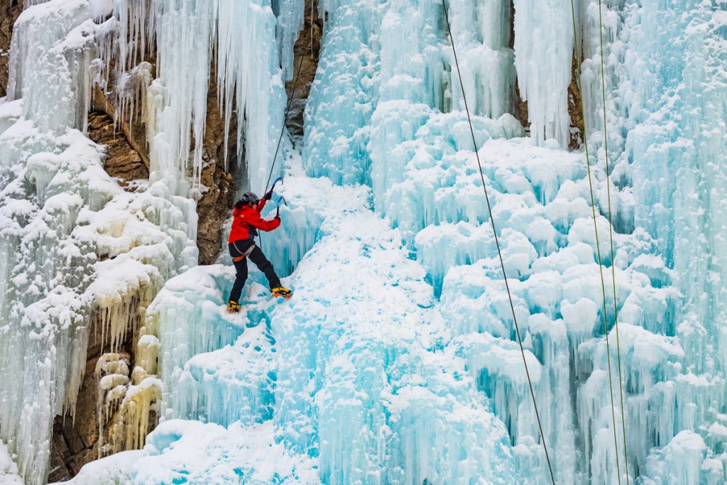A female ice climber climbing in the Beer Garden at the Lake City Ice Park in Colorado